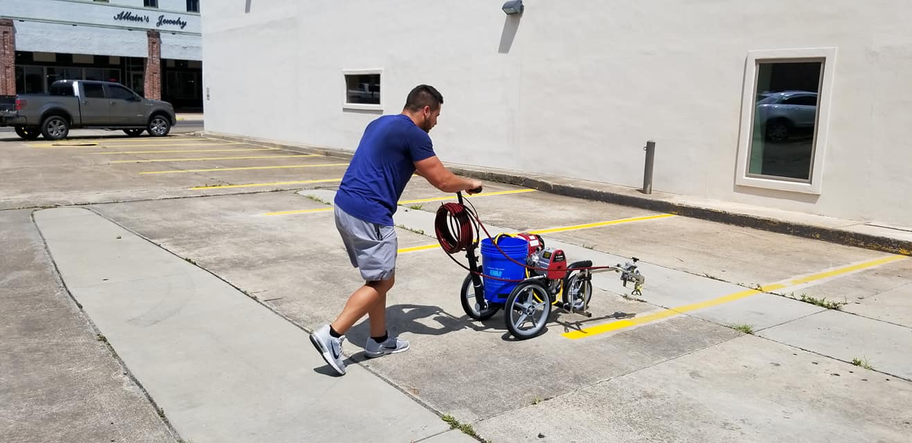 Third Coast Maintenance crew member striping parking lot lines at a Louisiana business